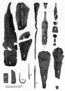 Kupferne Waffen und Werkzeuge aus den R-Gräbern. 1. Schwert R5; 2. Schwert R9; 3. Degen R7; 4. u. 5. Dolchreste R2a; 6. Dolch R7; 7. Dolch R9; 8. Dolch R5; 9. Dolch R2a; 10. u. 11. Plättchen R1 und 4a; 12. Haken R16; 13. u. 14. Stifte R16 und 10a.